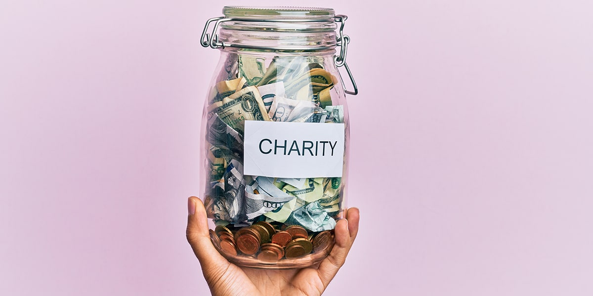 hand holding a jar with money saved up for charity