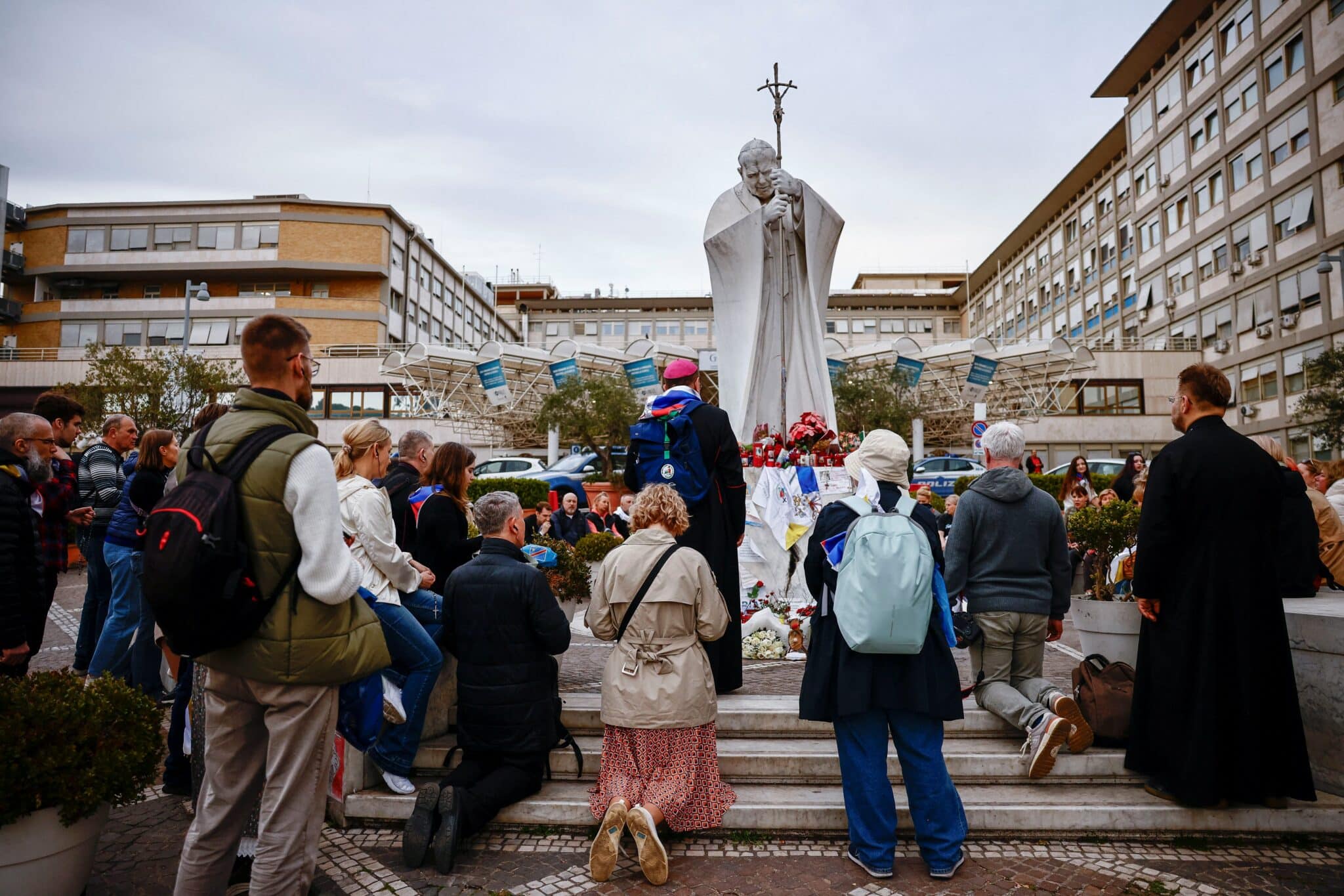 A group of Russian pilgrims prays during a rosary led by Archbishop Paolo Pezzi of Moscow, near a statue of St. John Paul II outside Rome's Gemelli Hospital .