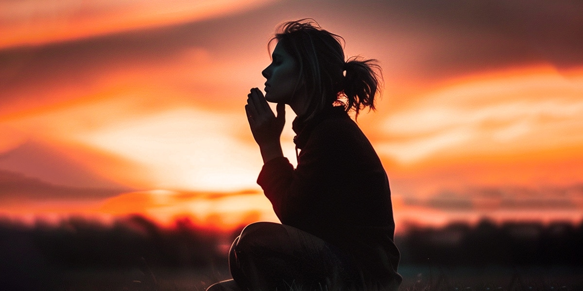 woman surrounded by peace praying during a sunset