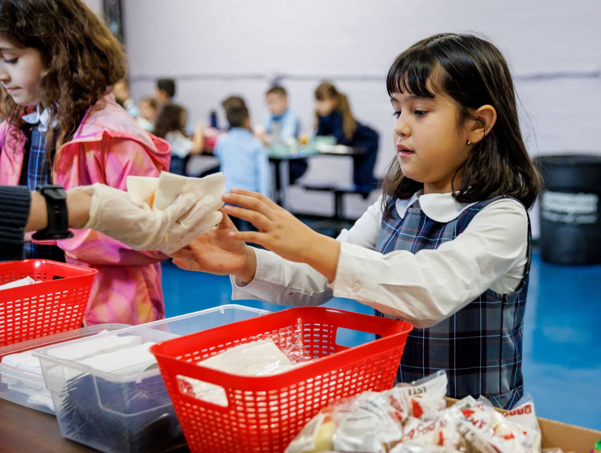 A student is handed a school lunch at Immaculate Conception School in Revere, Mass., March 21, 2025. The Trump administration cuts to federally funded school meal programs could leave thousands of kids hungry, said program administrators at Catholic dioceses.