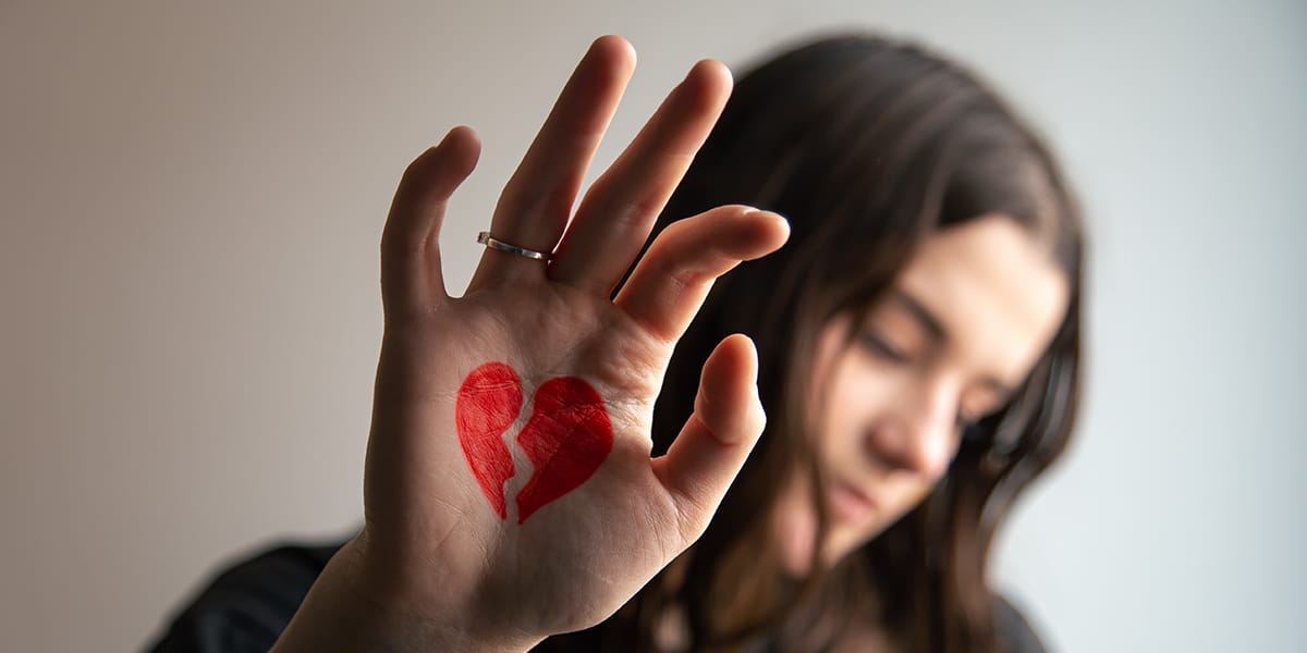 sad woman with a broken heart drawn on her hand